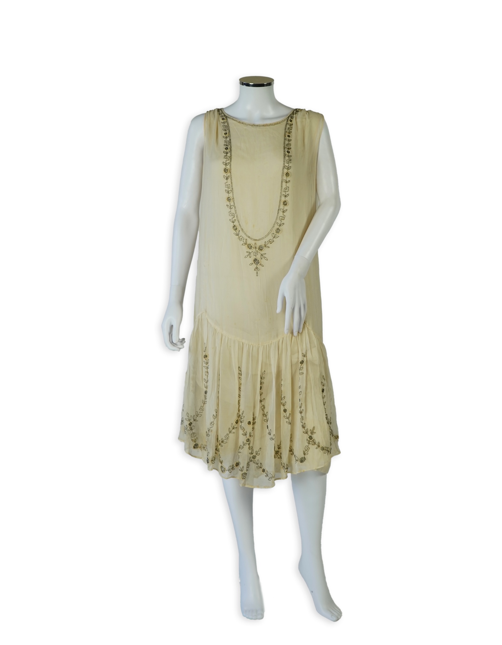 A 1920's cream silk georgette three quarter length, silk lined ‘flapper dress’. Designed with beaded and pearl floral embroidery, a stylish long beaded keyhole slit at the back, a beaded front bodice and flying beaded pa